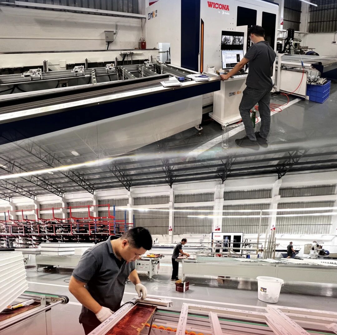 Factory technicians manually installing industrial rubber seals and gaskets on aluminum window frames