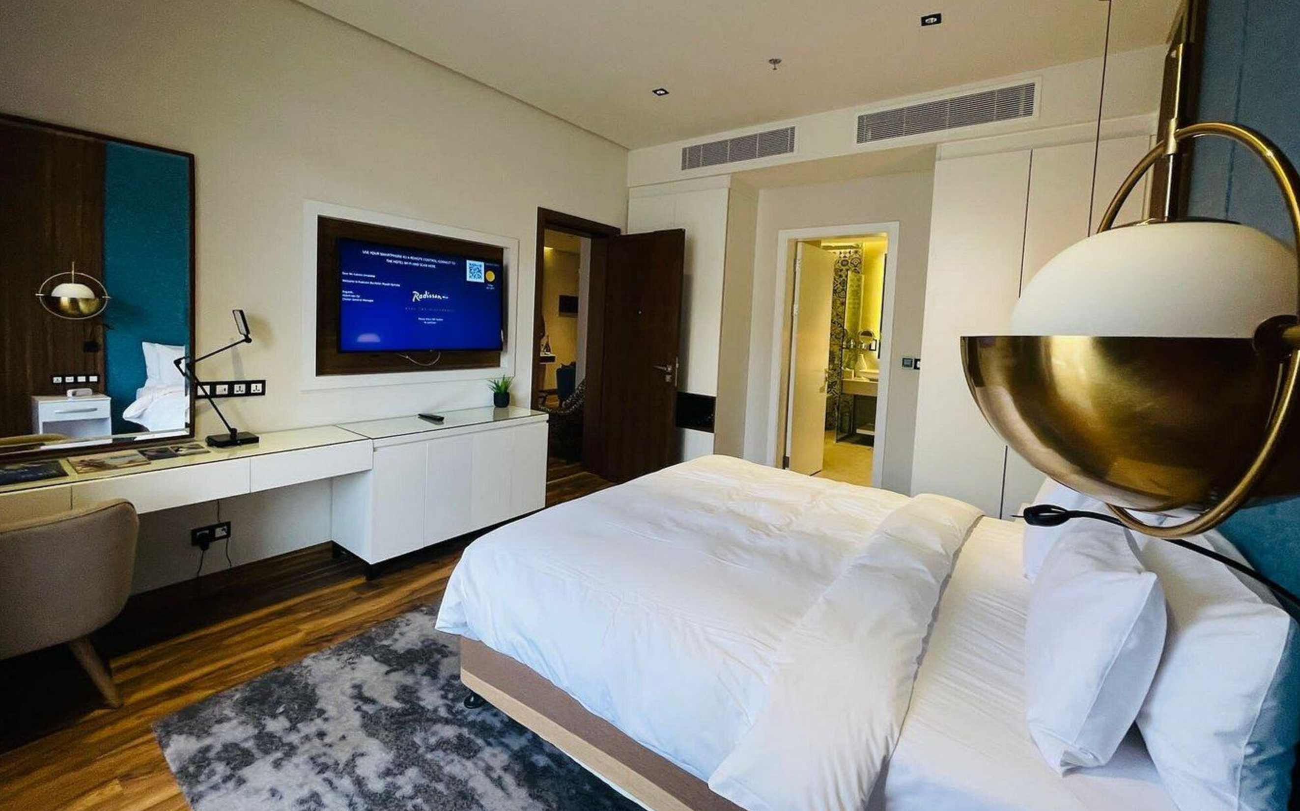 Hotel bedroom with premium white linens, pillows, and modern bedside lighting